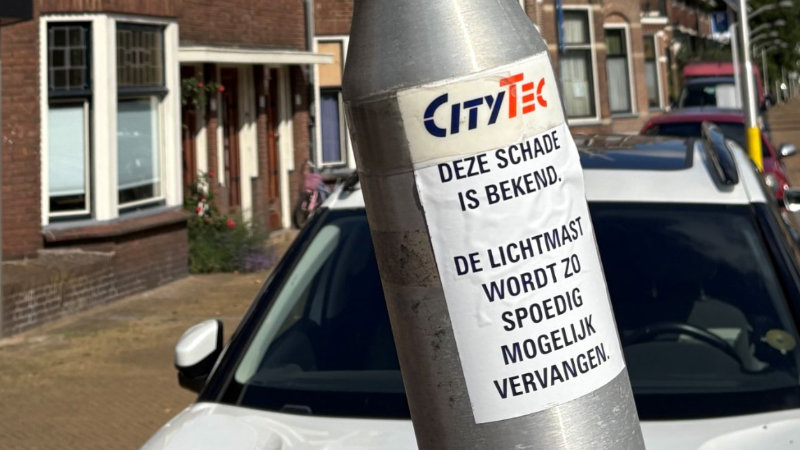 foto van een scheve lantarenpaal met een sticker waarop staat dat de schade bekend is en dat de paal vervangen zal worden.